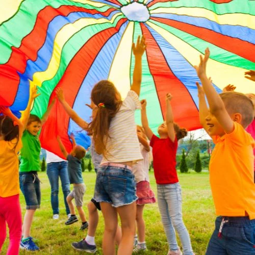 Children playing under a colorful parachute