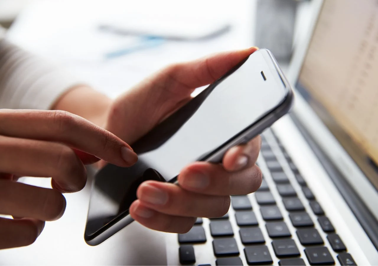 person using a cell phone and laptop