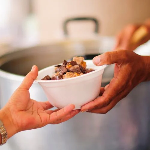 Person handing a bowl of food to anotoher