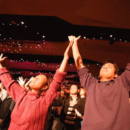 people at a worships service with hands raised